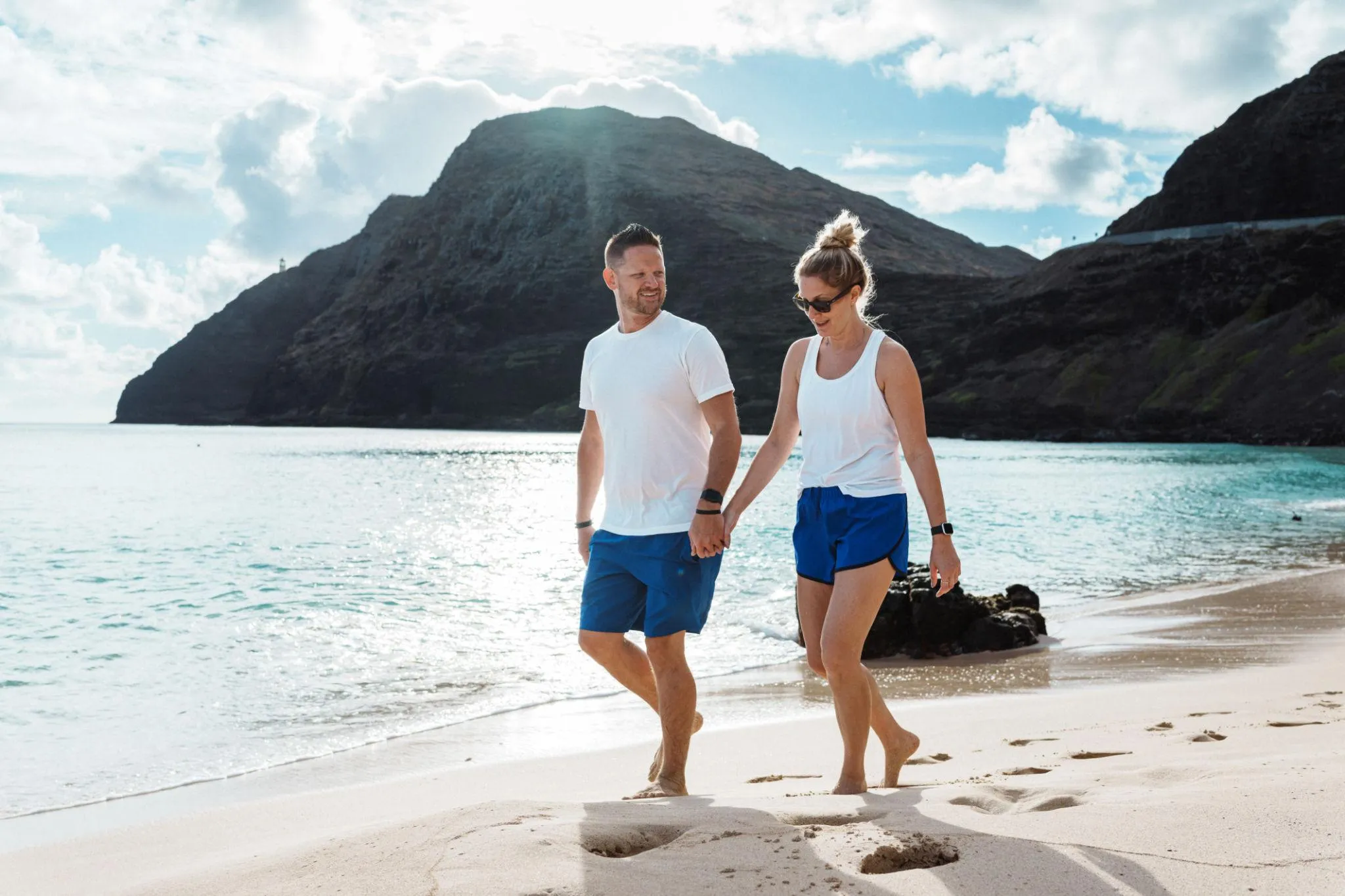 A couple walks along the shoreline of a Hawaiian beach
