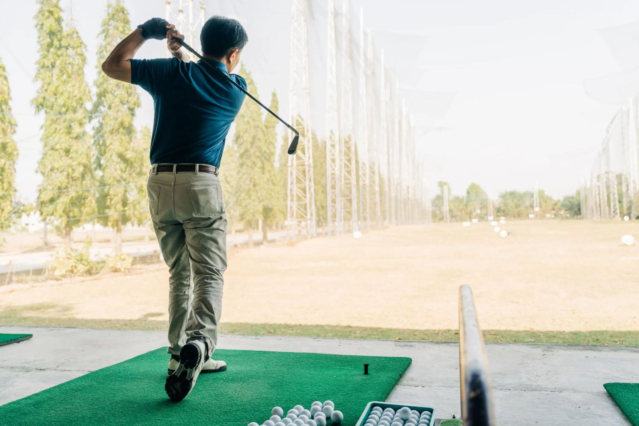 A golfer follows through on a swing at a driving range