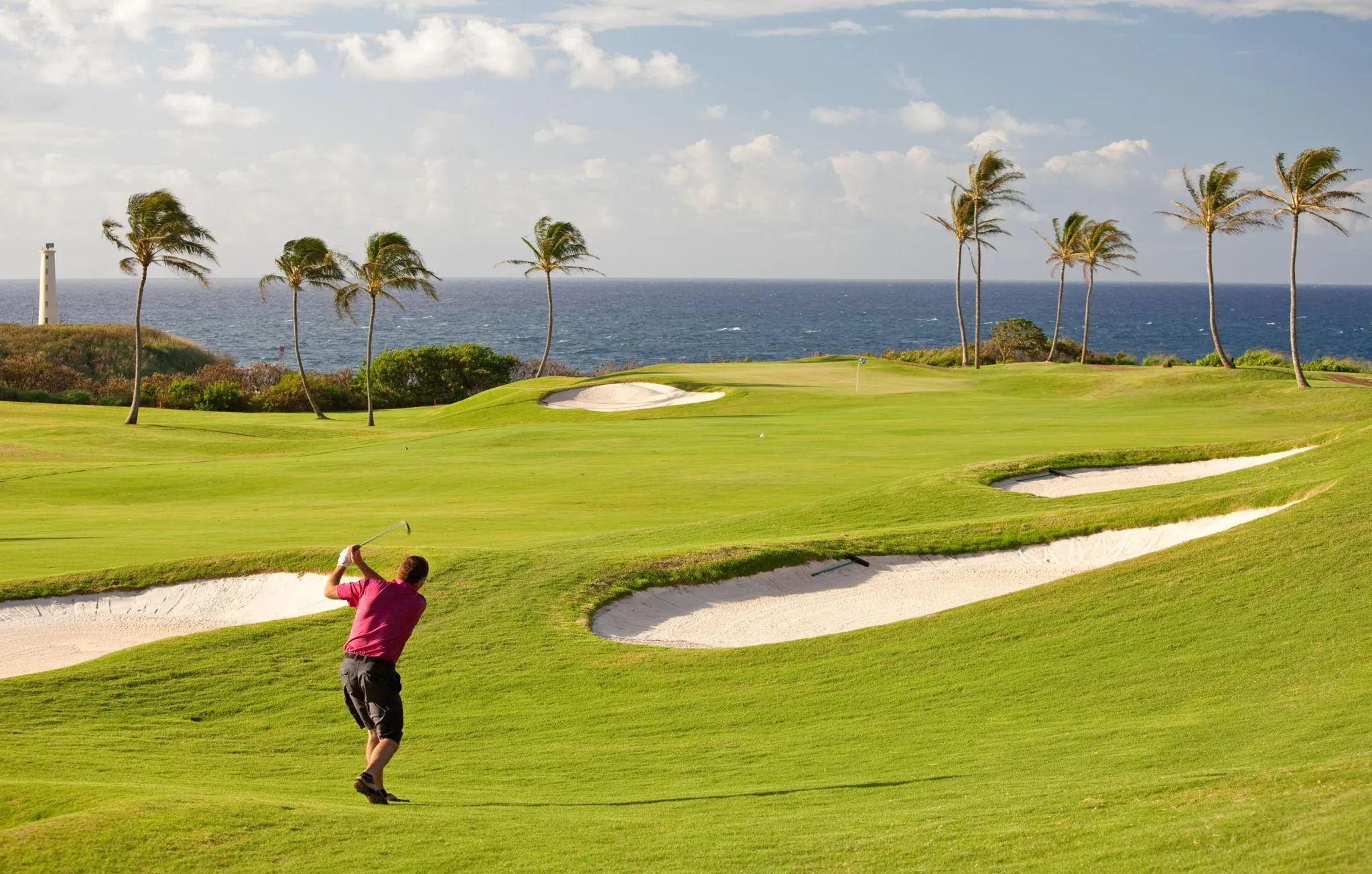 A golfer follows through on a swing at an oceanfront course in Hawai‘i