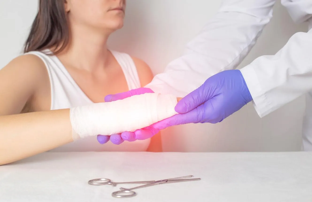 A clinician examines a patient's bandaged hand and wrist