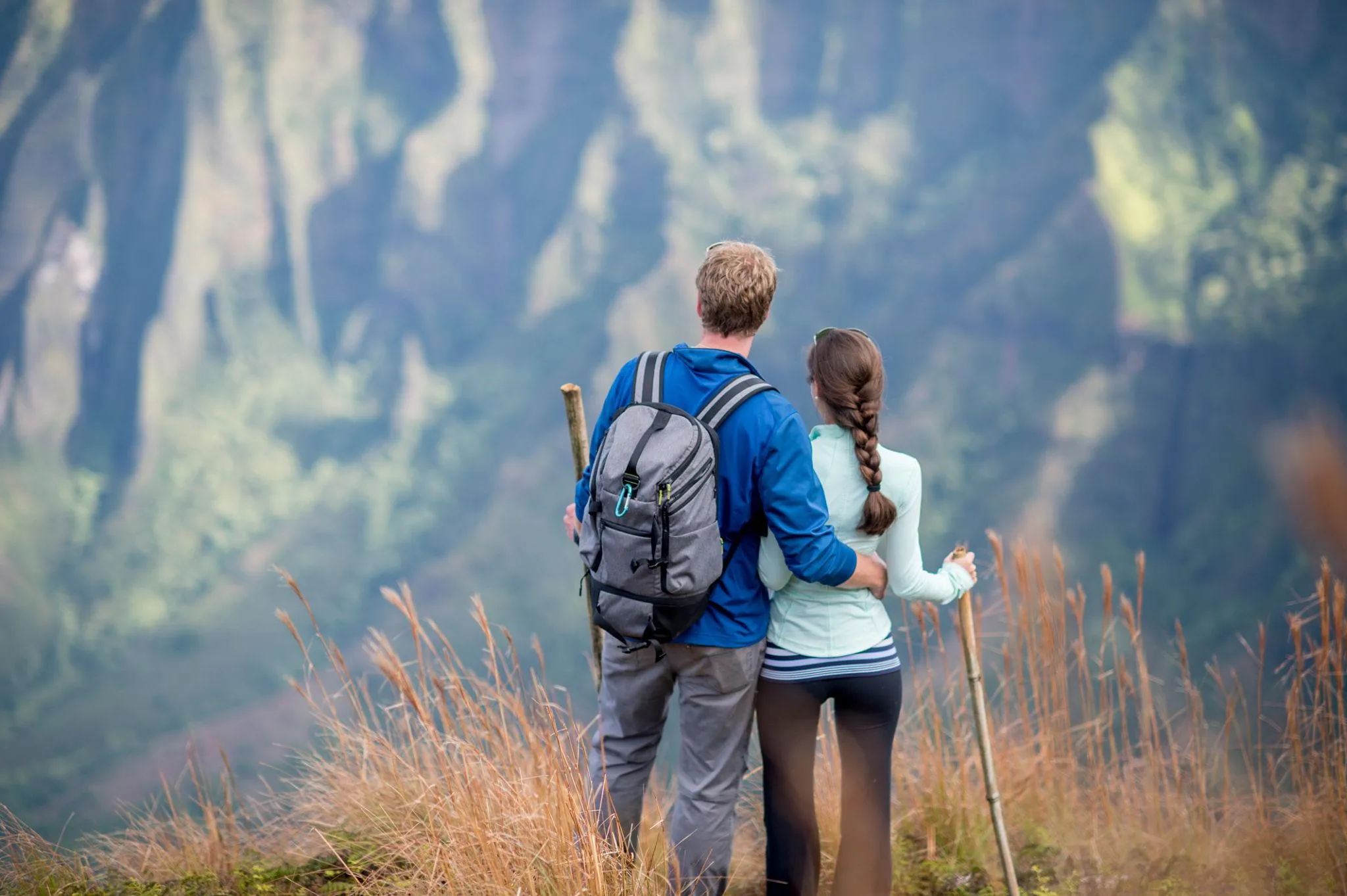 A couple pauses on a trail overlooking fluted sea cliffs in Hawai‘i
