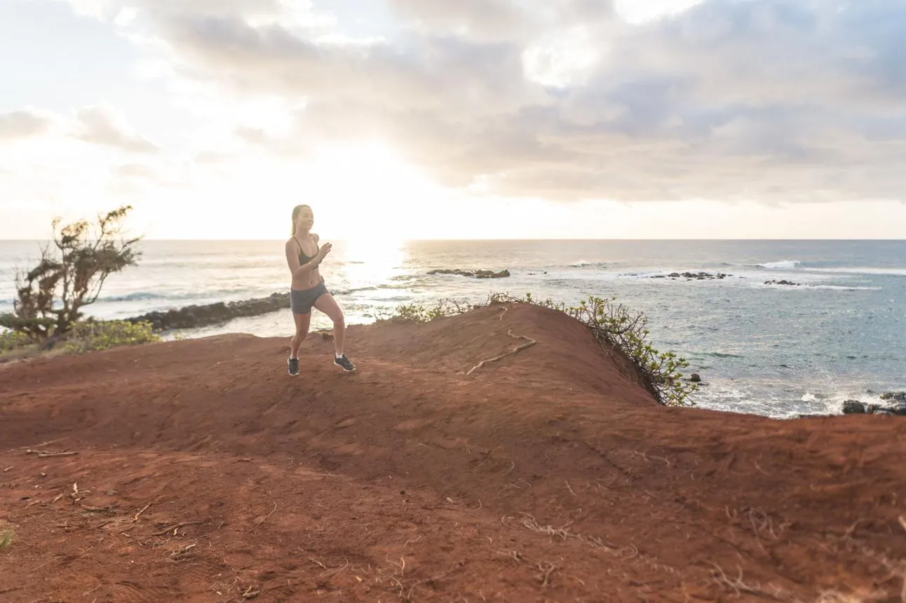 A runner on a coastal bluff trail above the ocean in Hawai‘i
