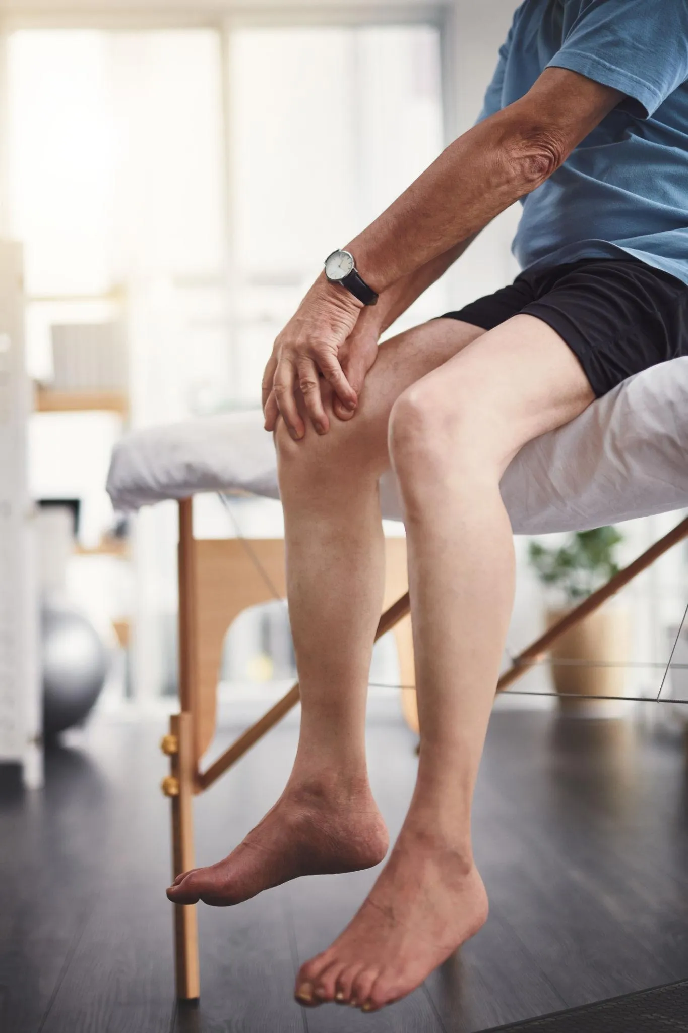 A patient holds their painful knee during a clinic evaluation