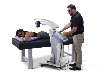 An MLS robotic laser unit positioned over a patient on a treatment table while a clinician operates the console
