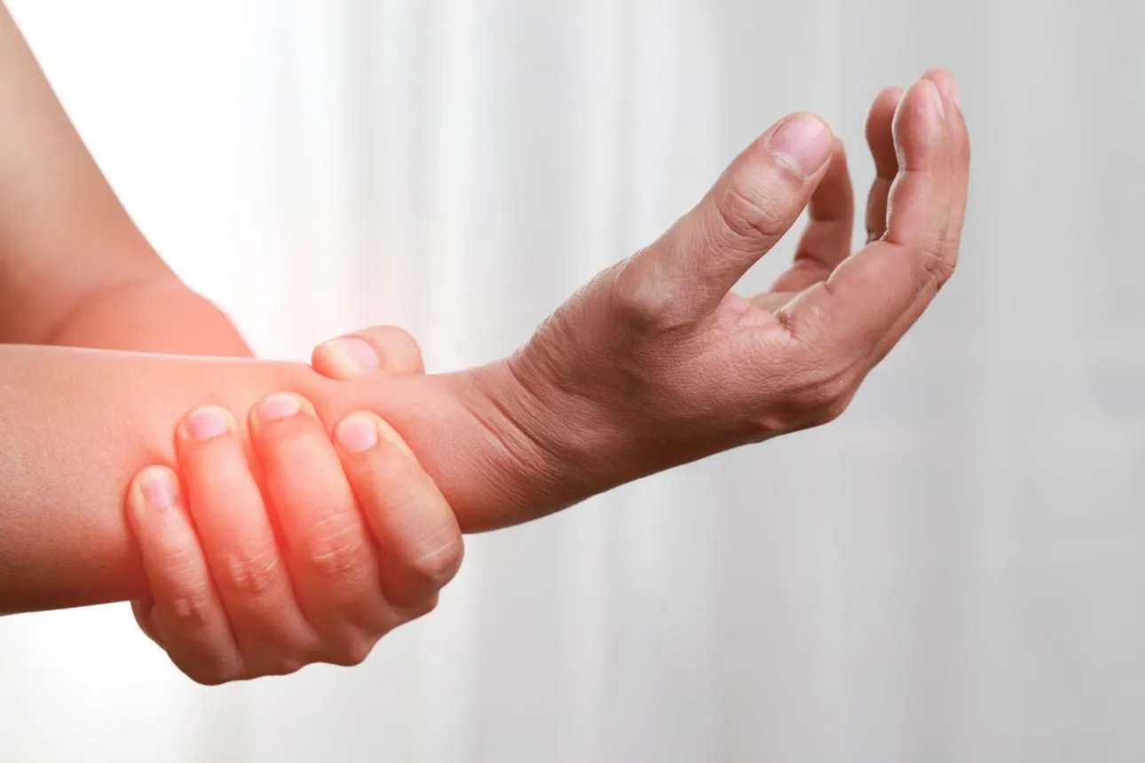 A person grips their aching wrist with both hands
